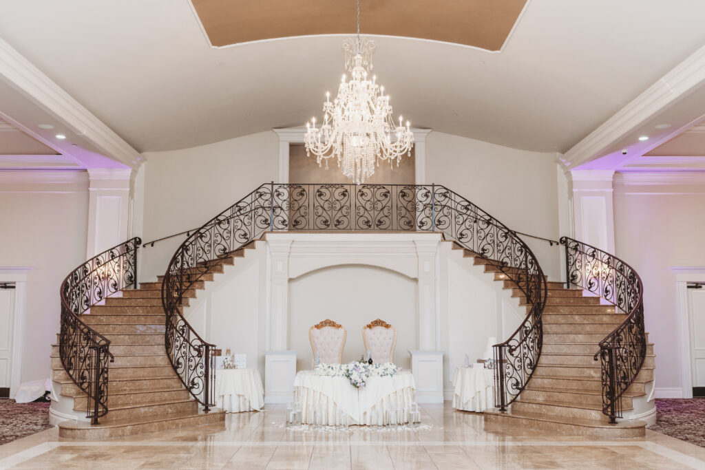 a sweetheart table positioned between a grand double staircase