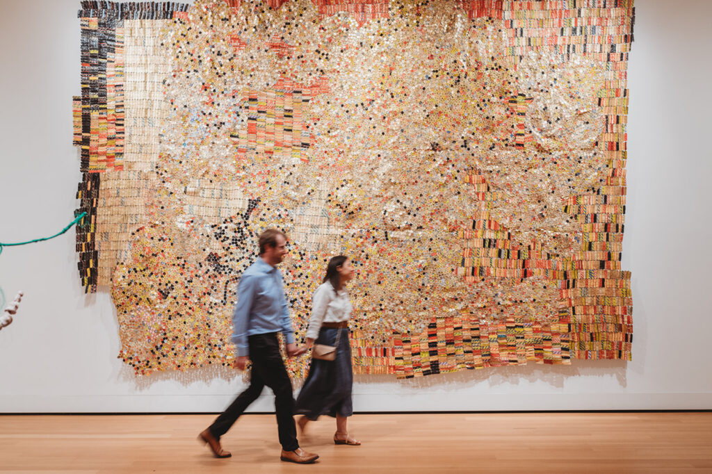 couple walks in front of larg golden art piece