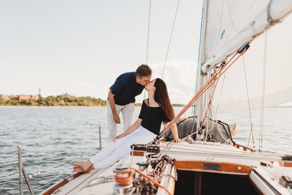 couple poses on boat in boston bay for their connecticut engagement photos