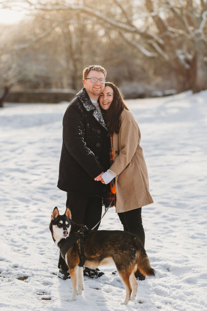 Engagement Photos with a dog and the couple smiles at the camera