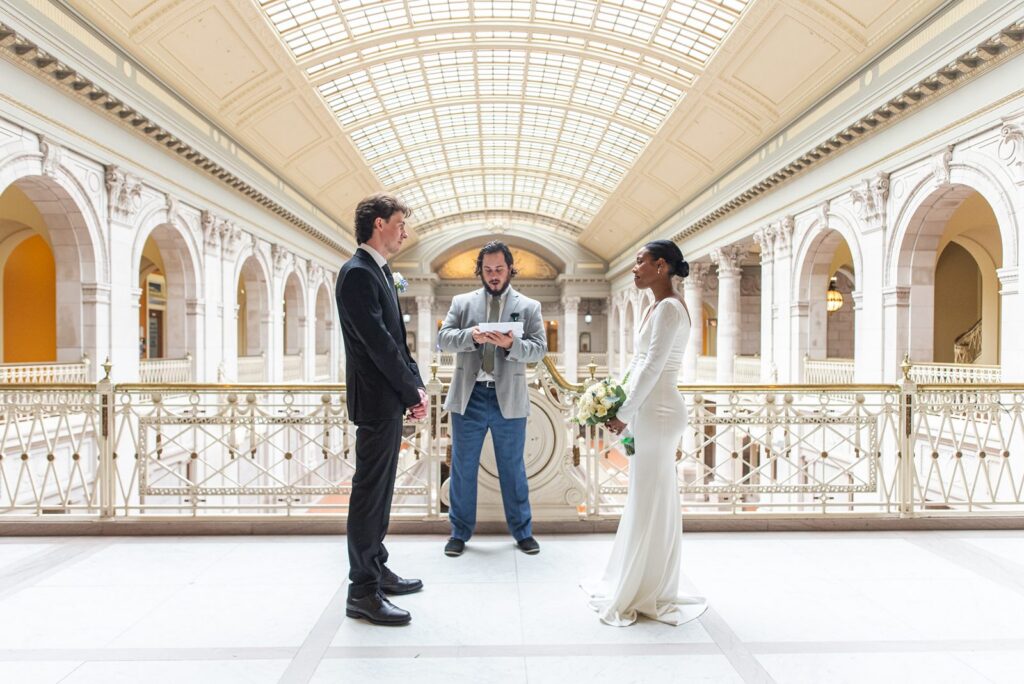 wide angle photo of couple getting married with hartford city hall architecture in back