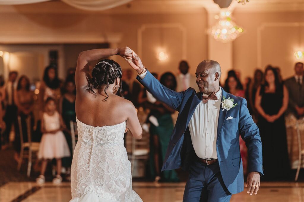 A bride is being spun by her dad during the first dance.