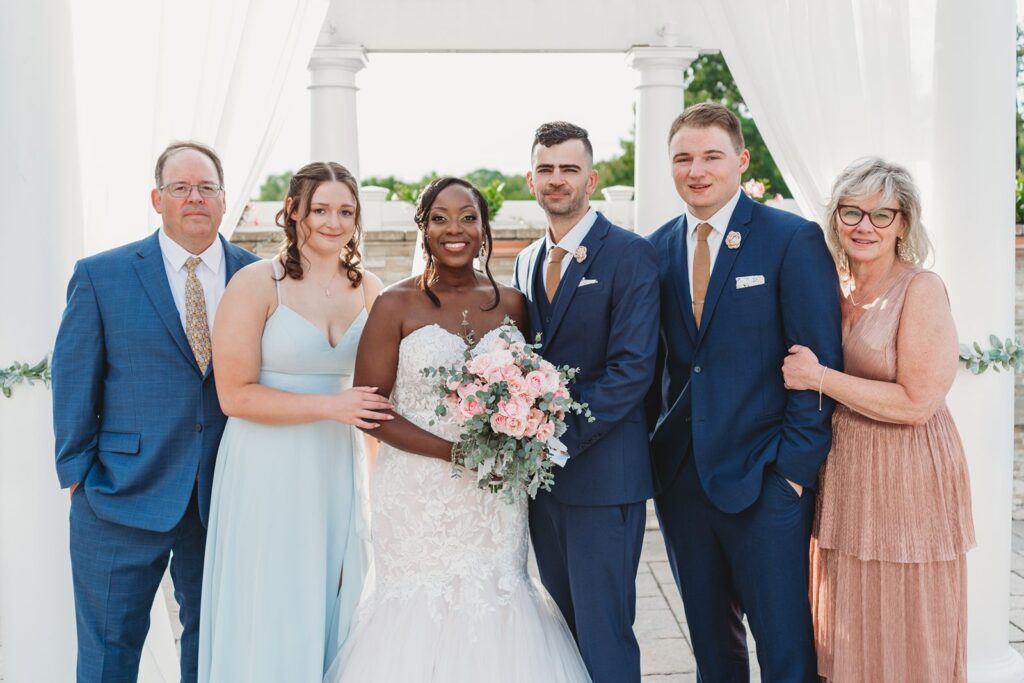 A family poses for a photo under the ceremony arbor.