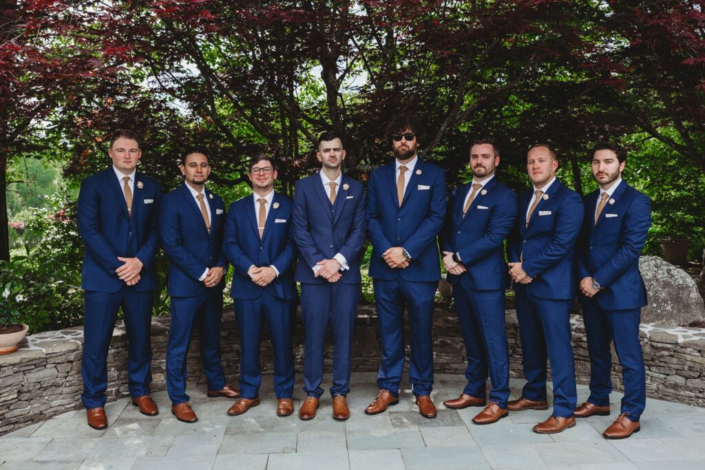 groomsmen pose for a formal photo by one of the garden areas at la bella vista.