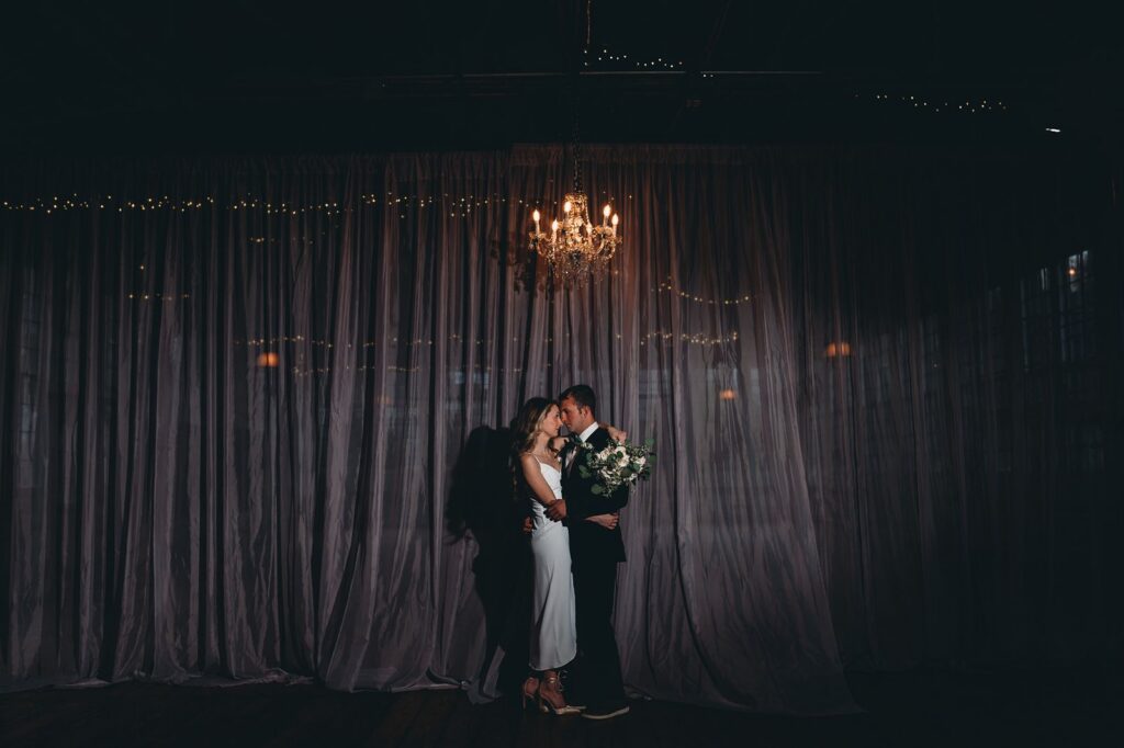 Couple standing under a chandelier lit by off camera flash