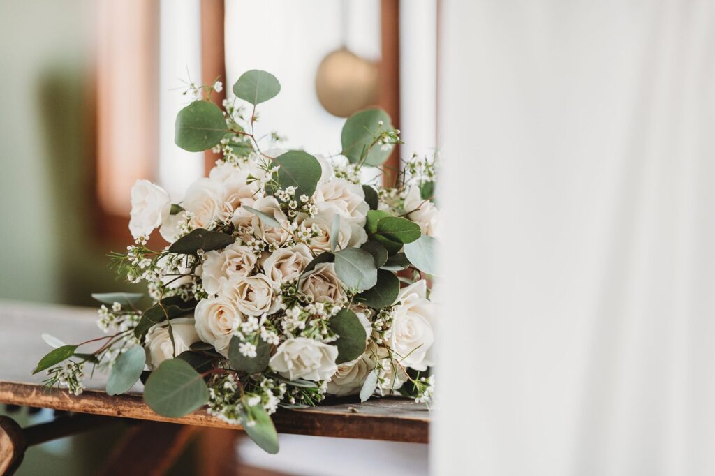 a bouquet of white flowers and green eucalyptus sitting on a table