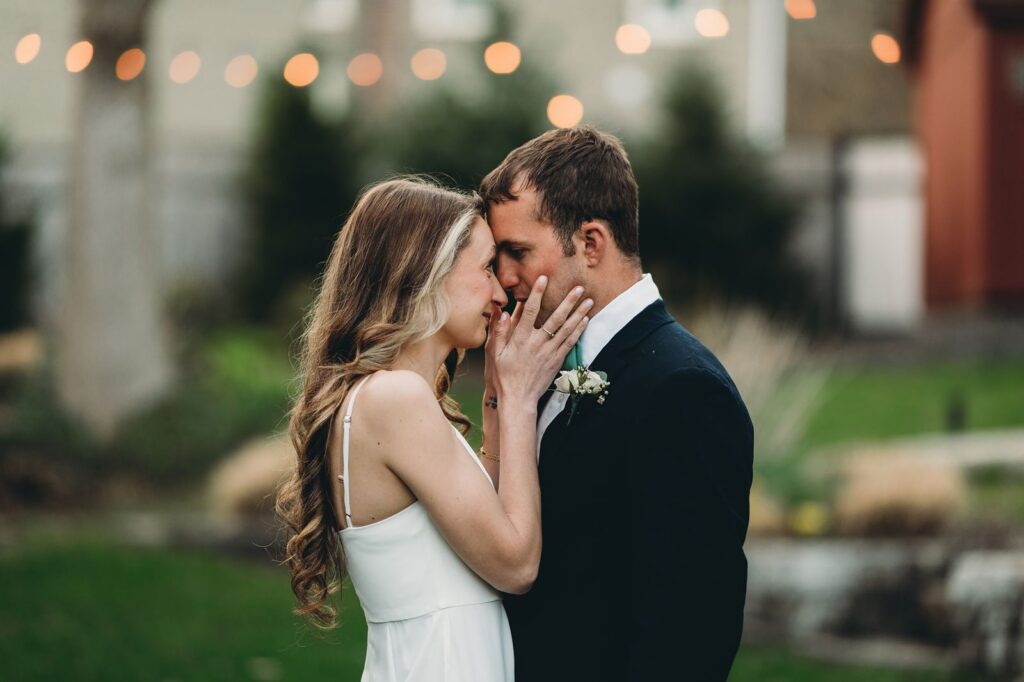 bride caressing grooms face outside at the lace factory