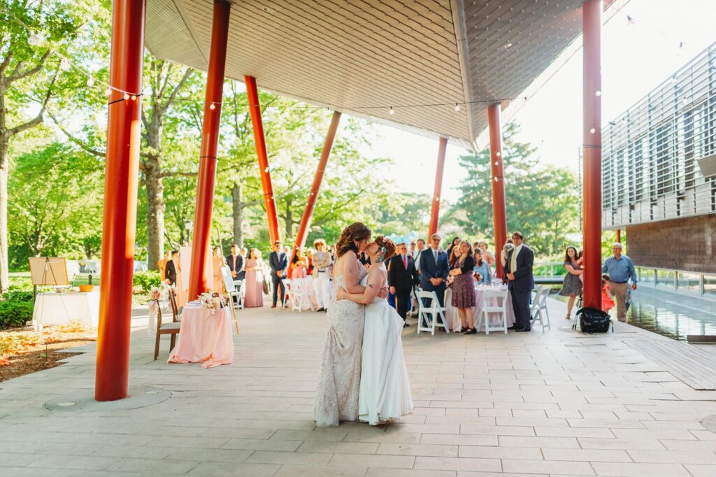 same sex couple shares their first dance under the beautiful terrace