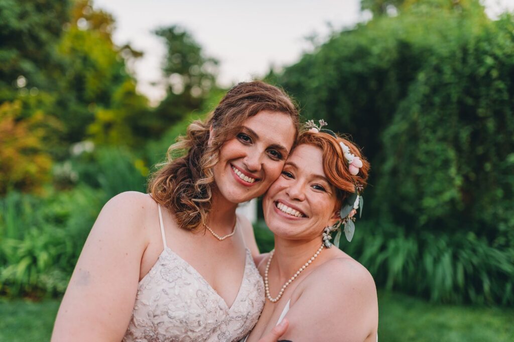 Two Brides smiling at the camera with their faces together