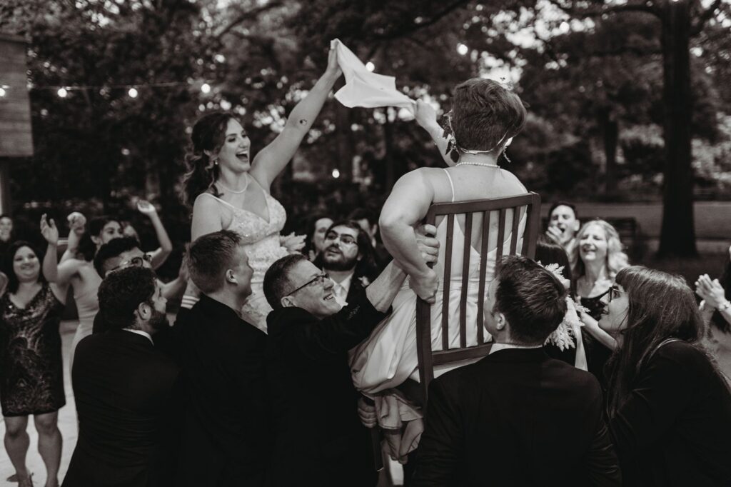brides laughing and waving napkin for Hora in black and white