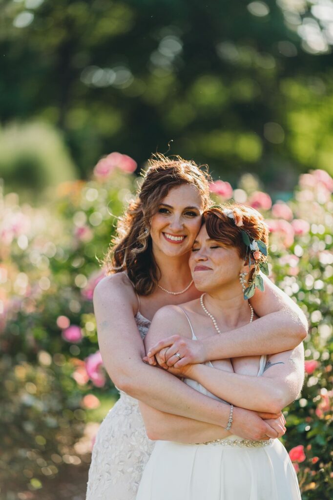 bride closes her eyes as her wife holds her in her arms in the queens botanical garden rose garden