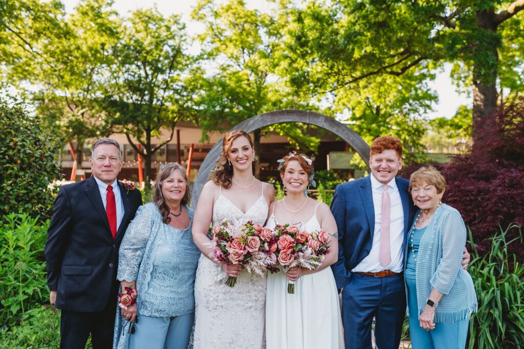 Brides with their family for a formal family portrait at the Queens Botanical Garden
