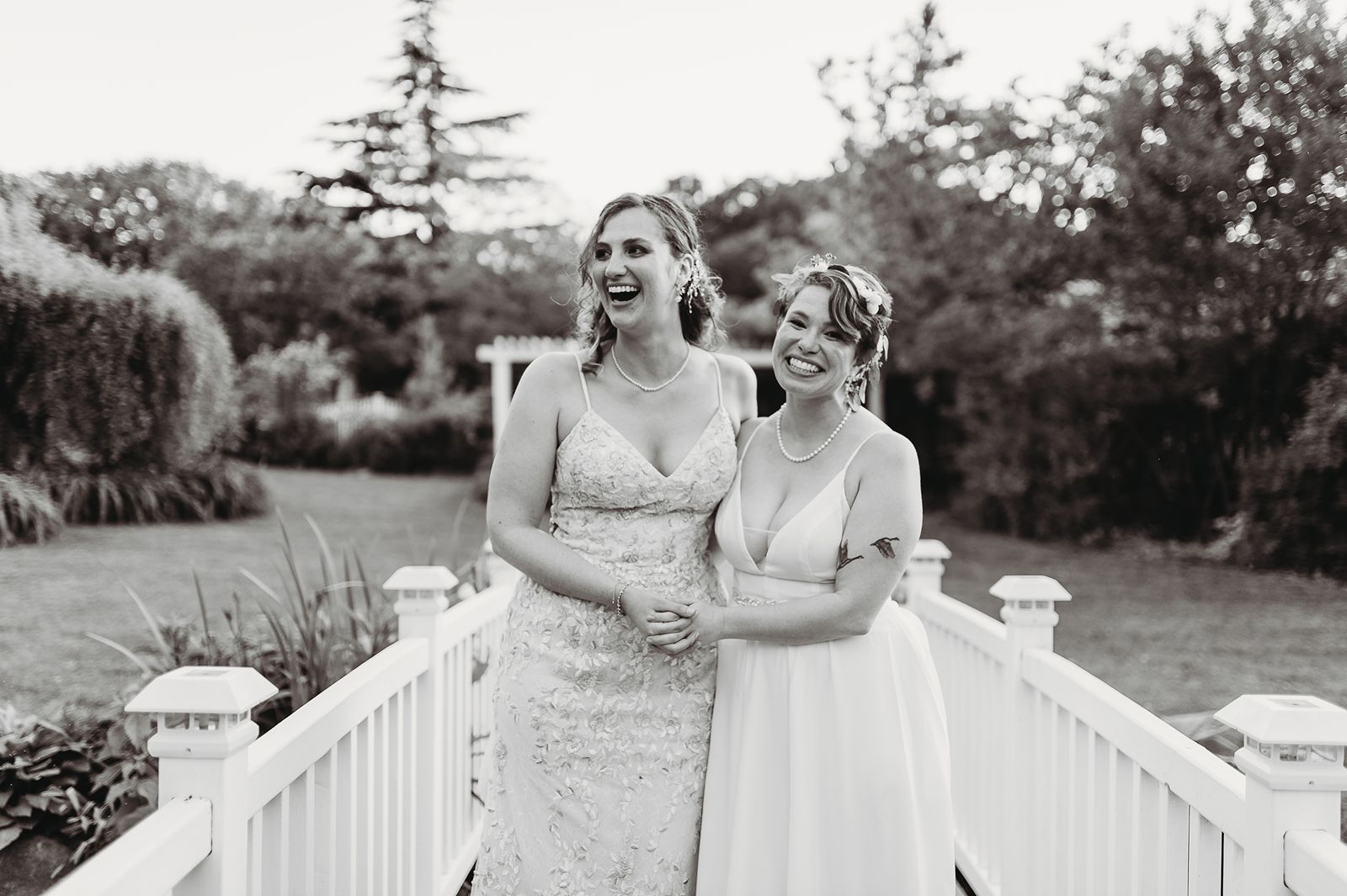a bride and her wife holding hands on the bridge at the queens botanical garden