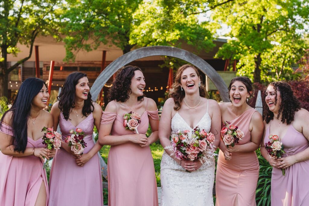 bride laughing with her bridesmaids all in pink at the Botanical Garden