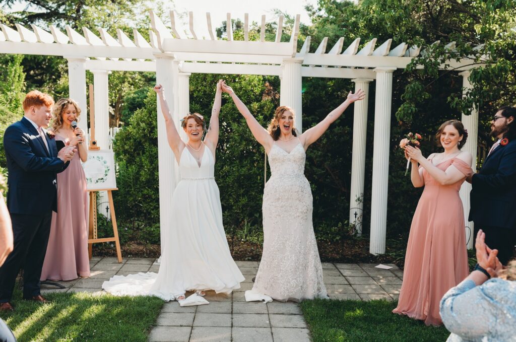 couple cheering after they shared their first kiss and the breaking of the glass at the Queens Botanical Garden