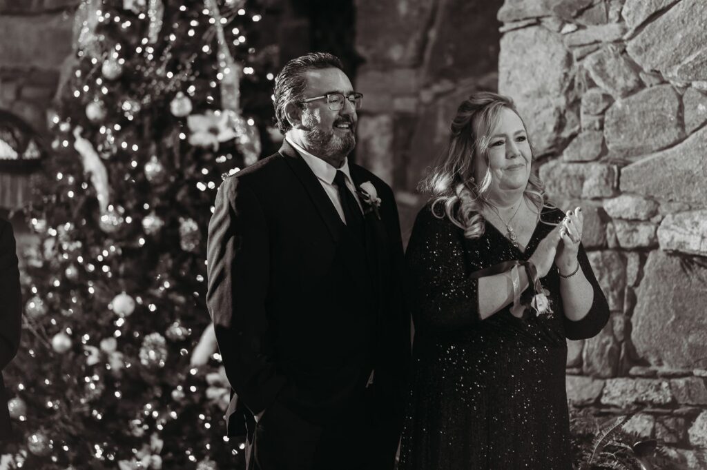 a mom and dad watch their daughter have her first dance at bill miller's castle with a christmas tree behind them